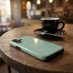 Handyhülle mit Motiv BE BLESSED in mintgrün auf Holztisch neben schwarzer Kaffeetasse, Lifestyle