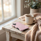 Robuste Handyhülle BE BLESSED in Rosa neben Kaffeetasse und Strickdecke auf rustikalem Holztisch – Lifestyle