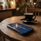 Handyhülle mit Motiv FORGIVEN in Dunkelblau auf Holztisch neben Kaffeetasse im Café, Lifestyle