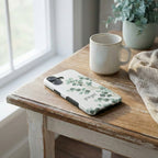 Handyhülle mit Motiv GESEGNET in Weiß mit botanischem Eukalyptus-Design auf Holztisch – Lifestyle