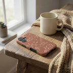 Handyhülle Glaube Loved by the King in Terrakotta mit weißem Blumenmotiv neben Tasse – Lifestyle